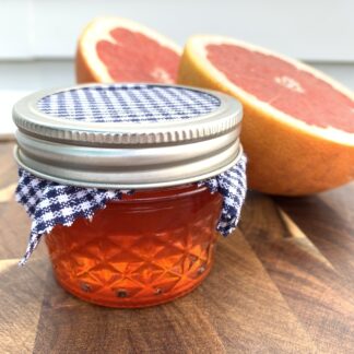 Bright pink marmalade in a small quilted glass jar.